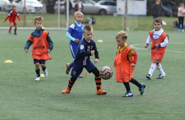 ODESSA, UKRAINE - 25 Eylül 2021: Küçük çocuklar, küçük çocuklar spor şampiyonası kasabasında yapay sahada futbol oynuyorlar. Çocuk sporları sağlıklı yaşam tarzıdır. Spor çocukları futbol oyuncuları
