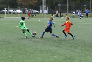 ODESSA, UKRAINE - 25 Eylül 2021: Küçük çocuklar, küçük çocuklar spor şampiyonası kasabasında yapay sahada futbol oynuyorlar. Çocuk sporları sağlıklı yaşam tarzıdır. Spor çocukları futbol oyuncuları