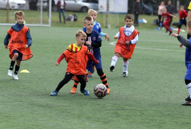 ODESSA, UKRAINE - 25 Eylül 2021: Küçük çocuklar, küçük çocuklar spor şampiyonası kasabasında yapay sahada futbol oynuyorlar. Çocuk sporları sağlıklı yaşam tarzıdır. Spor çocukları futbol oyuncuları
