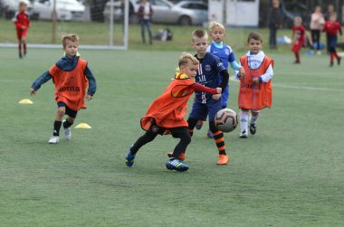 ODESSA, UKRAINE - 25 Eylül 2021: Küçük çocuklar, küçük çocuklar spor şampiyonası kasabasında yapay sahada futbol oynuyorlar. Çocuk sporları sağlıklı yaşam tarzıdır. Spor çocukları futbol oyuncuları