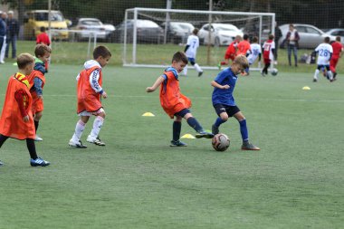 ODESSA, UKRAINE - 25 Eylül 2021: Küçük çocuklar, küçük çocuklar spor şampiyonası kasabasında yapay sahada futbol oynuyorlar. Çocuk sporları sağlıklı yaşam tarzıdır. Spor çocukları futbol oyuncuları