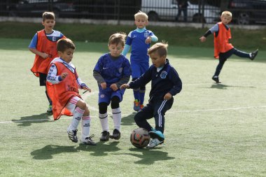 ODESSA, UKRAINE - 25 Eylül 2021: Küçük çocuklar, küçük çocuklar spor şampiyonası kasabasında yapay sahada futbol oynuyorlar. Çocuk sporları sağlıklı yaşam tarzıdır. Spor çocukları futbol oyuncuları