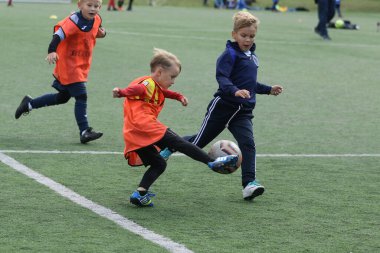 ODESSA, UKRAINE - 25 Eylül 2021: Küçük çocuklar, küçük çocuklar spor şampiyonası kasabasında yapay sahada futbol oynuyorlar. Çocuk sporları sağlıklı yaşam tarzıdır. Spor çocukları futbol oyuncuları