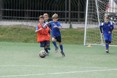 ODESSA, UKRAINE - 25 Eylül 2021: Küçük çocuklar, küçük çocuklar spor şampiyonası kasabasında yapay sahada futbol oynuyorlar. Çocuk sporları sağlıklı yaşam tarzıdır. Spor çocukları futbol oyuncuları