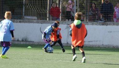 ODESSA, UKRAINE - 25 Eylül 2021: Küçük çocuklar, küçük çocuklar spor şampiyonası kasabasında yapay sahada futbol oynuyorlar. Çocuk sporları sağlıklı yaşam tarzıdır. Spor çocukları futbol oyuncuları