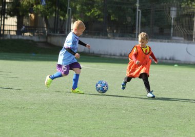 ODESSA, UKRAINE - 25 Eylül 2021: Küçük çocuklar, küçük çocuklar spor şampiyonası kasabasında yapay sahada futbol oynuyorlar. Çocuk sporları sağlıklı yaşam tarzıdır. Spor çocukları futbol oyuncuları