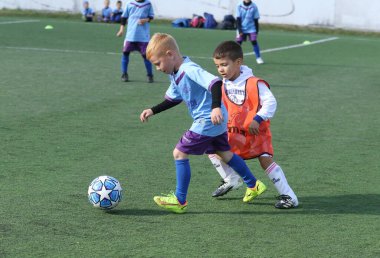 ODESSA, UKRAINE - 25 Eylül 2021: Küçük çocuklar, küçük çocuklar spor şampiyonası kasabasında yapay sahada futbol oynuyorlar. Çocuk sporları sağlıklı yaşam tarzıdır. Spor çocukları futbol oyuncuları