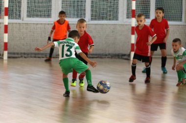 ODESSA, UKRAINE - 14 Ekim 2021: Küçük çocuklar 8-9 yaşlarında, Ukrayna Şampiyonası 'nda spor salonunda mini futbol oynuyorlar. Çocuk sporları sağlıklı yaşam tarzıdır. Erkek sporcular futsal yapıyor.