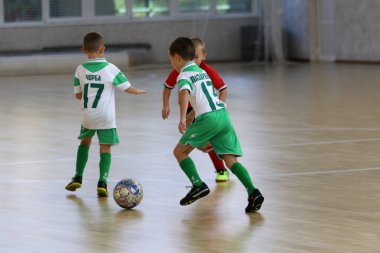 ODESSA, UKRAINE - 14 Ekim 2021: Küçük çocuklar 8-9 yaşlarında, Ukrayna Şampiyonası 'nda spor salonunda mini futbol oynuyorlar. Çocuk sporları sağlıklı yaşam tarzıdır. Erkek sporcular futsal yapıyor.