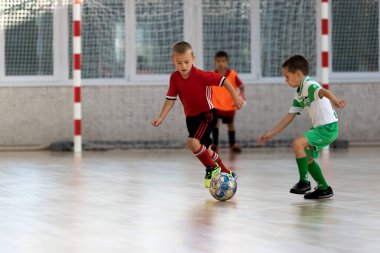 ODESSA, UKRAINE - 14 Ekim 2021: Küçük çocuklar 8-9 yaşlarında, Ukrayna Şampiyonası 'nda spor salonunda mini futbol oynuyorlar. Çocuk sporları sağlıklı yaşam tarzıdır. Erkek sporcular futsal yapıyor.