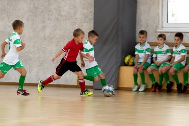 ODESSA, UKRAINE - 14 Ekim 2021: Küçük çocuklar 8-9 yaşlarında, Ukrayna Şampiyonası 'nda spor salonunda mini futbol oynuyorlar. Çocuk sporları sağlıklı yaşam tarzıdır. Erkek sporcular futsal yapıyor.