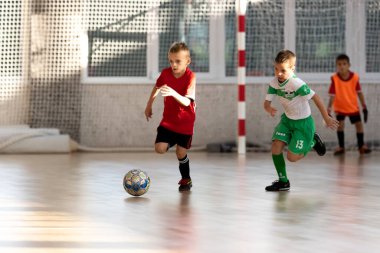 ODESSA, UKRAINE - 14 Ekim 2021: Küçük çocuklar 8-9 yaşlarında, Ukrayna Şampiyonası 'nda spor salonunda mini futbol oynuyorlar. Çocuk sporları sağlıklı yaşam tarzıdır. Erkek sporcular futsal yapıyor.
