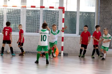 ODESSA, UKRAINE - 14 Ekim 2021: Küçük çocuklar 8-9 yaşlarında, Ukrayna Şampiyonası 'nda spor salonunda mini futbol oynuyorlar. Çocuk sporları sağlıklı yaşam tarzıdır. Erkek sporcular futsal yapıyor.