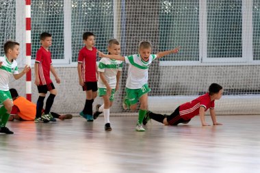 ODESSA, UKRAINE - 14 Ekim 2021: Küçük çocuklar 8-9 yaşlarında, Ukrayna Şampiyonası 'nda spor salonunda mini futbol oynuyorlar. Çocuk sporları sağlıklı yaşam tarzıdır. Erkek sporcular futsal yapıyor.