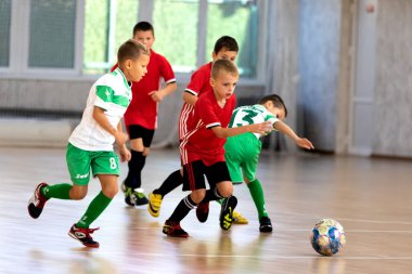 ODESSA, UKRAINE - 14 Ekim 2021: Küçük çocuklar 8-9 yaşlarında, Ukrayna Şampiyonası 'nda spor salonunda mini futbol oynuyorlar. Çocuk sporları sağlıklı yaşam tarzıdır. Erkek sporcular futsal yapıyor.