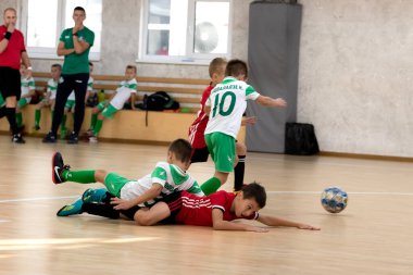 ODESSA, UKRAINE - 14 Ekim 2021: Küçük çocuklar 8-9 yaşlarında, Ukrayna Şampiyonası 'nda spor salonunda mini futbol oynuyorlar. Çocuk sporları sağlıklı yaşam tarzıdır. Erkek sporcular futsal yapıyor.