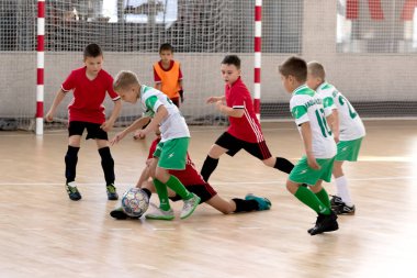 ODESSA, UKRAINE - 14 Ekim 2021: Küçük çocuklar 8-9 yaşlarında, Ukrayna Şampiyonası 'nda spor salonunda mini futbol oynuyorlar. Çocuk sporları sağlıklı yaşam tarzıdır. Erkek sporcular futsal yapıyor.