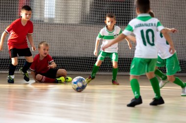 ODESSA, UKRAINE - 14 Ekim 2021: Küçük çocuklar 8-9 yaşlarında, Ukrayna Şampiyonası 'nda spor salonunda mini futbol oynuyorlar. Çocuk sporları sağlıklı yaşam tarzıdır. Erkek sporcular futsal yapıyor.