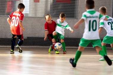 ODESSA, UKRAINE - 14 Ekim 2021: Küçük çocuklar 8-9 yaşlarında, Ukrayna Şampiyonası 'nda spor salonunda mini futbol oynuyorlar. Çocuk sporları sağlıklı yaşam tarzıdır. Erkek sporcular futsal yapıyor.