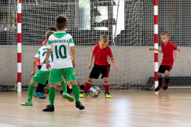 ODESSA, UKRAINE - 14 Ekim 2021: Küçük çocuklar 8-9 yaşlarında, Ukrayna Şampiyonası 'nda spor salonunda mini futbol oynuyorlar. Çocuk sporları sağlıklı yaşam tarzıdır. Erkek sporcular futsal yapıyor.