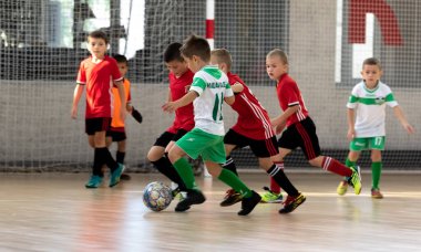 ODESSA, UKRAINE - 14 Ekim 2021: Küçük çocuklar 8-9 yaşlarında, Ukrayna Şampiyonası 'nda spor salonunda mini futbol oynuyorlar. Çocuk sporları sağlıklı yaşam tarzıdır. Erkek sporcular futsal yapıyor.