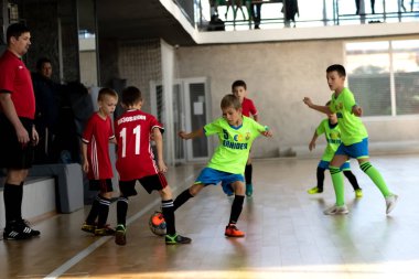 ODESSA, UKRAINE - 14 Ekim 2021: Küçük çocuklar 8-9 yaşlarında, Ukrayna Şampiyonası 'nda spor salonunda mini futbol oynuyorlar. Çocuk sporları sağlıklı yaşam tarzıdır. Erkek sporcular futsal yapıyor.