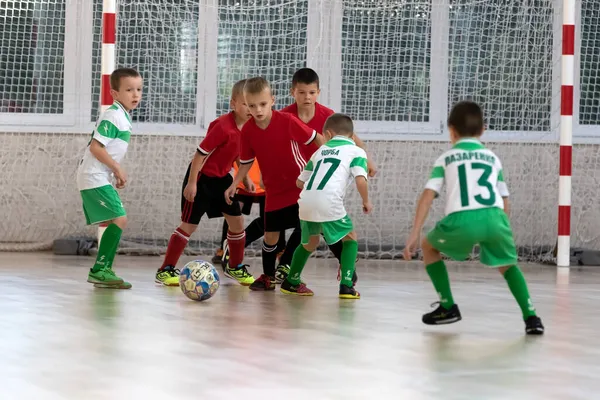 ODESSA, UKRAINE - 14 Ekim 2021: Küçük çocuklar 8-9 yaşlarında, Ukrayna Şampiyonası 'nda spor salonunda mini futbol oynuyorlar. Çocuk sporları sağlıklı yaşam tarzıdır. Erkek sporcular futsal yapıyor.