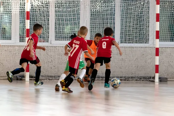 ODESSA, UKRAINE - 14 Ekim 2021: Küçük çocuklar 8-9 yaşlarında, Ukrayna Şampiyonası 'nda spor salonunda mini futbol oynuyorlar. Çocuk sporları sağlıklı yaşam tarzıdır. Erkek sporcular futsal yapıyor.