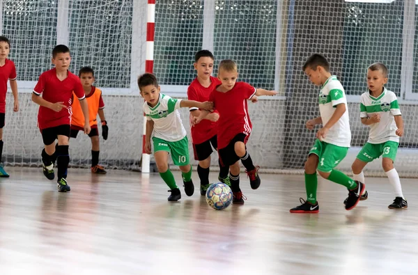 ODESSA, UKRAINE - 14 Ekim 2021: Küçük çocuklar 8-9 yaşlarında, Ukrayna Şampiyonası 'nda spor salonunda mini futbol oynuyorlar. Çocuk sporları sağlıklı yaşam tarzıdır. Erkek sporcular futsal yapıyor.