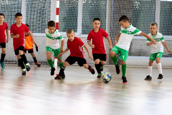 ODESSA, UKRAINE - 14 Ekim 2021: Küçük çocuklar 8-9 yaşlarında, Ukrayna Şampiyonası 'nda spor salonunda mini futbol oynuyorlar. Çocuk sporları sağlıklı yaşam tarzıdır. Erkek sporcular futsal yapıyor.