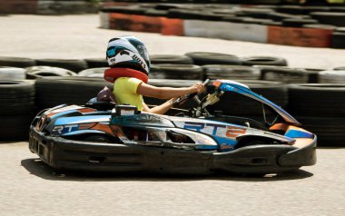 ODESSA, UKRAINE - 18 Haziran 2022: Karting. Devam et Kart. Otomobil pistinde araba yarışı sırasında kask takan genç pozitif kız yarışçı. Spor kulübünde aşırı otomobil sporu