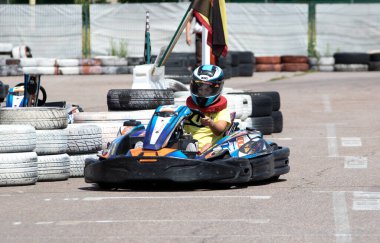 ODESSA, UKRAINE - 18 Haziran 2022: Karting. Devam et Kart. Otomobil pistinde araba yarışı sırasında kask takan genç pozitif kız yarışçı. Spor kulübünde aşırı otomobil sporu