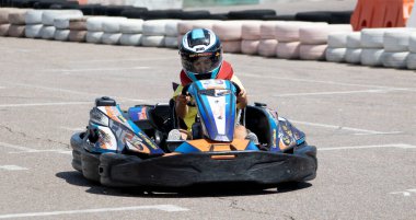 ODESSA, UKRAINE - 18 Haziran 2022: Karting. Devam et Kart. Otomobil pistinde araba yarışı sırasında kask takan genç pozitif kız yarışçı. Spor kulübünde aşırı otomobil sporu