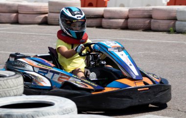 ODESSA, UKRAINE - 18 Haziran 2022: Karting. Devam et Kart. Otomobil pistinde araba yarışı sırasında kask takan genç pozitif kız yarışçı. Spor kulübünde aşırı otomobil sporu