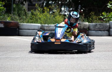 ODESSA, UKRAINE - 18 Haziran 2022: Karting. Devam et Kart. Otomobil pistinde araba yarışı sırasında kask takan genç pozitif kız yarışçı. Spor kulübünde aşırı otomobil sporu