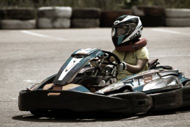 ODESSA, UKRAINE - 18 Haziran 2022: Karting. Devam et Kart. Otomobil pistinde araba yarışı sırasında kask takan genç pozitif kız yarışçı. Spor kulübünde aşırı otomobil sporu