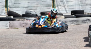 ODESSA, UKRAINE - 18 Haziran 2022: Karting. Devam et Kart. Otomobil pistinde araba yarışı sırasında kask takan genç pozitif kız yarışçı. Spor kulübünde aşırı otomobil sporu