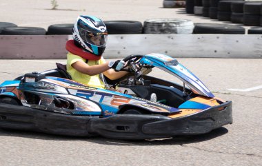 ODESSA, UKRAINE - 18 Haziran 2022: Karting. Devam et Kart. Otomobil pistinde araba yarışı sırasında kask takan genç pozitif kız yarışçı. Spor kulübünde aşırı otomobil sporu