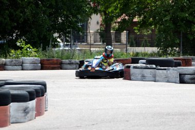 ODESSA, UKRAINE - 18 Haziran 2022: Karting. Devam et Kart. Otomobil pistinde araba yarışı sırasında kask takan genç pozitif kız yarışçı. Spor kulübünde aşırı otomobil sporu
