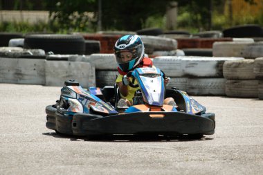 ODESSA, UKRAINE - 18 Haziran 2022: Karting. Devam et Kart. Otomobil pistinde araba yarışı sırasında kask takan genç pozitif kız yarışçı. Spor kulübünde aşırı otomobil sporu