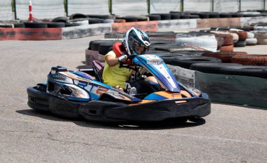 ODESSA, UKRAINE - 18 Haziran 2022: Karting. Devam et Kart. Otomobil pistinde araba yarışı sırasında kask takan genç pozitif kız yarışçı. Spor kulübünde aşırı otomobil sporu