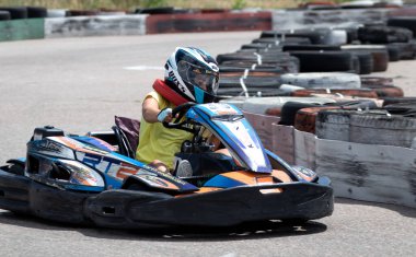 ODESSA, UKRAINE - 18 Haziran 2022: Karting. Devam et Kart. Otomobil pistinde araba yarışı sırasında kask takan genç pozitif kız yarışçı. Spor kulübünde aşırı otomobil sporu