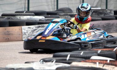 ODESSA, UKRAINE - 18 Haziran 2022: Karting. Devam et Kart. Otomobil pistinde araba yarışı sırasında kask takan genç pozitif kız yarışçı. Spor kulübünde aşırı otomobil sporu