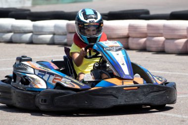 ODESSA, UKRAINE - 18 Haziran 2022: Karting. Devam et Kart. Otomobil pistinde araba yarışı sırasında kask takan genç pozitif kız yarışçı. Spor kulübünde aşırı otomobil sporu