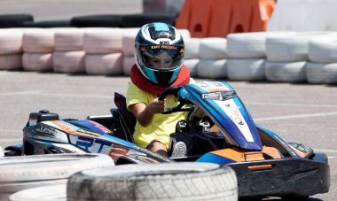 ODESSA, UKRAINE - 18 Haziran 2022: Karting. Devam et Kart. Otomobil pistinde araba yarışı sırasında kask takan genç pozitif kız yarışçı. Spor kulübünde aşırı otomobil sporu