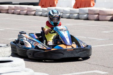 ODESSA, UKRAINE - 18 Haziran 2022: Karting. Devam et Kart. Otomobil pistinde araba yarışı sırasında kask takan genç pozitif kız yarışçı. Spor kulübünde aşırı otomobil sporu