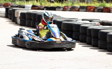 ODESSA, UKRAINE - 18 Haziran 2022: Karting. Devam et Kart. Otomobil pistinde araba yarışı sırasında kask takan genç pozitif kız yarışçı. Spor kulübünde aşırı otomobil sporu