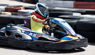 ODESSA, UKRAINE - 18 Haziran 2022: Karting. Devam et Kart. Otomobil pistinde araba yarışı sırasında kask takan genç pozitif kız yarışçı. Spor kulübünde aşırı otomobil sporu
