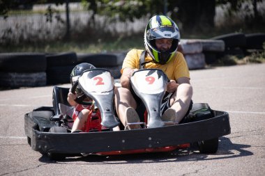 ODESSA, UKRAINE - August 7, 2022: Healthy lifestyle. Sport family. Family vacation at karting track. Children with parents go in for motorsports. Karting. Hobbies, sports education, leisure, lifestyle