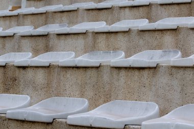 The interior of a football stadium without spectators. Seats for spectators on the stadium podium. Old worn plastic chairs for spectators of sports football matches